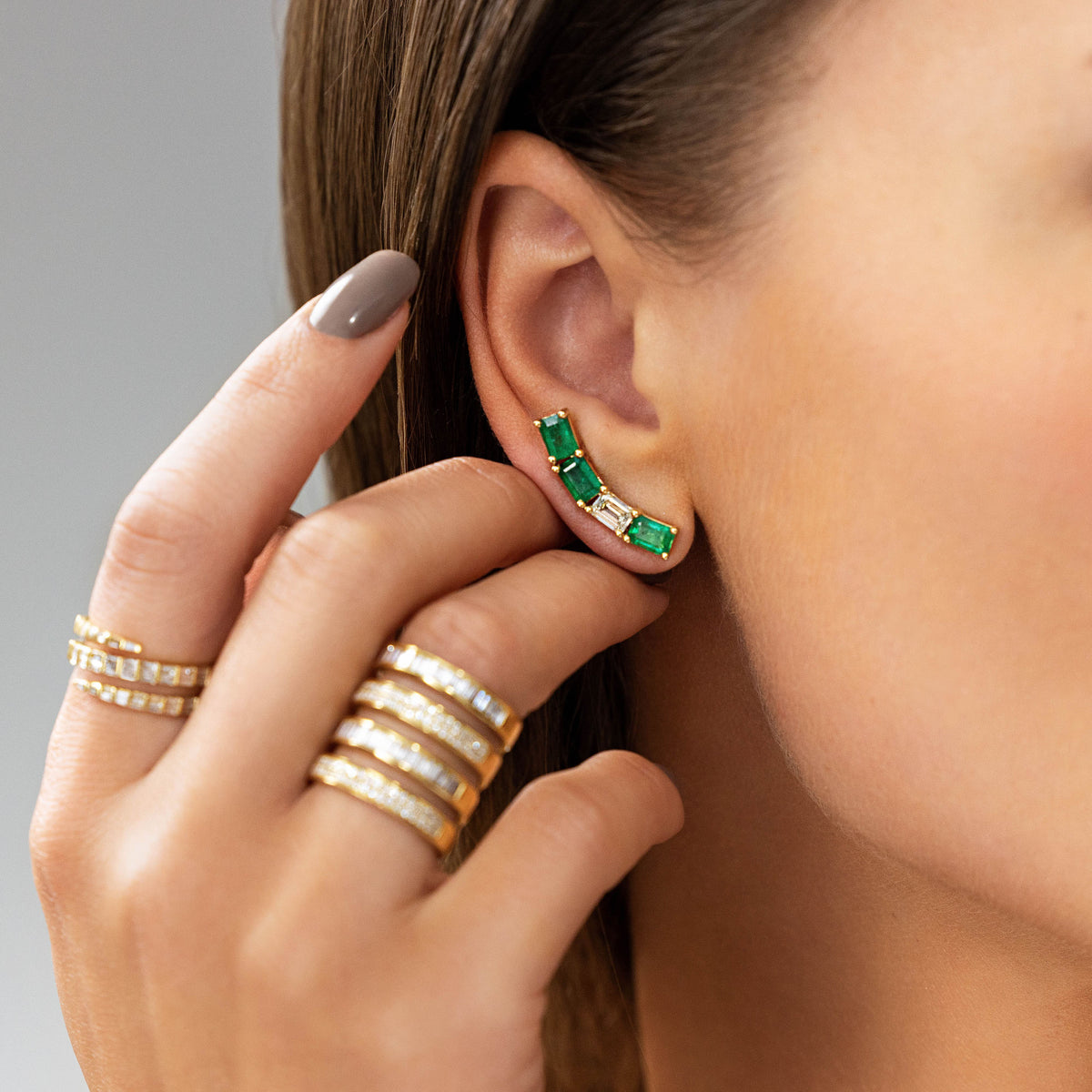 Emerald and Diamond Baguette Ear Crawlers in 18K Yellow Gold, styled with diamond rings | JJ Jewelry Miami