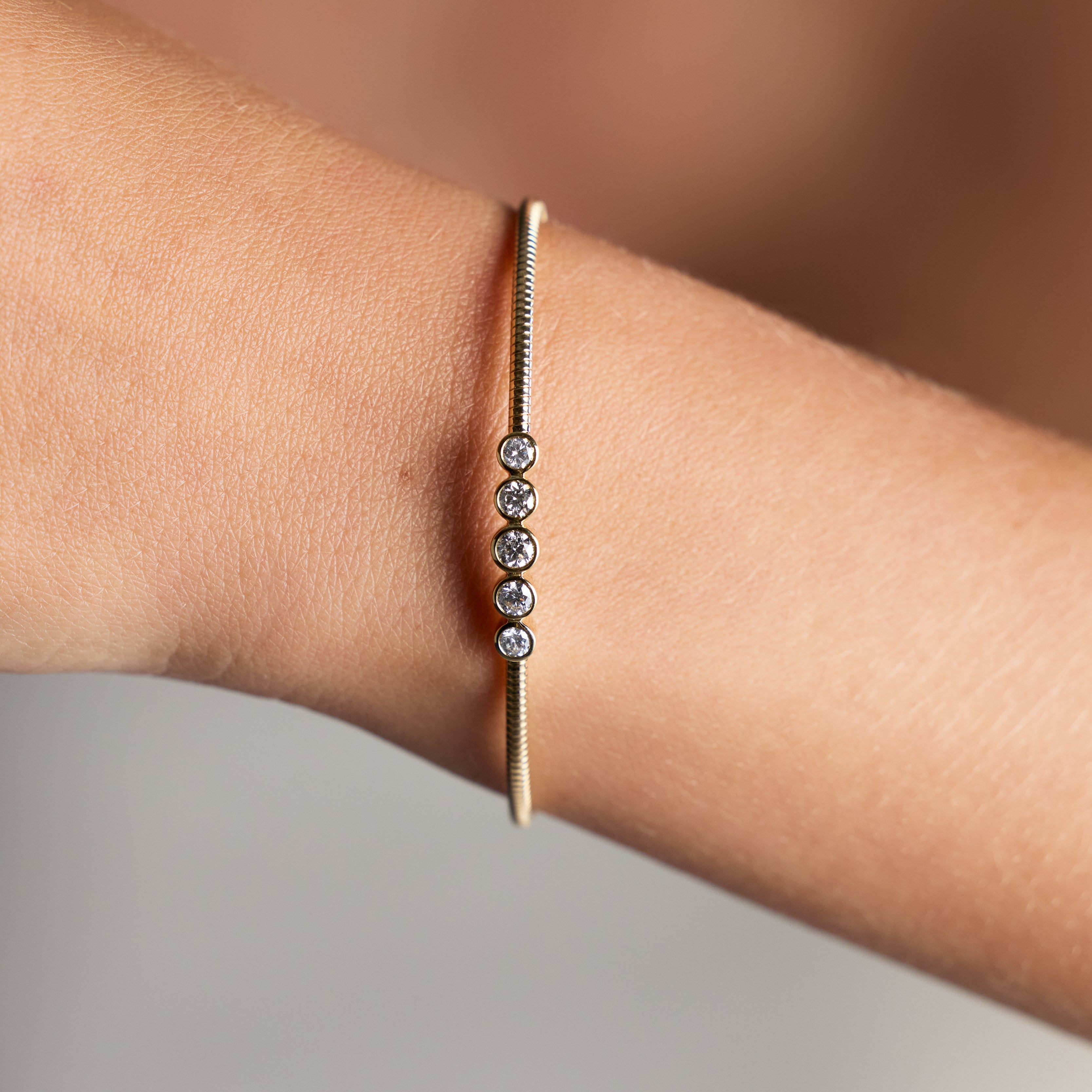 18K yellow gold flexible bangle with five round brilliant diamonds