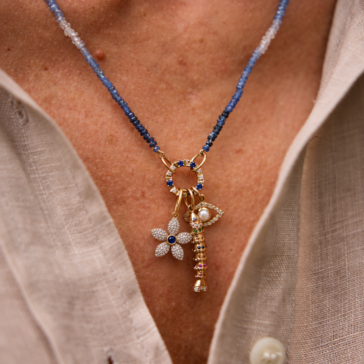 Pavé Diamond Flower Pendant with Gemstone Center in 14K White Gold, on a blue sapphire bead necklace with charms | JJ Jewelry Miami